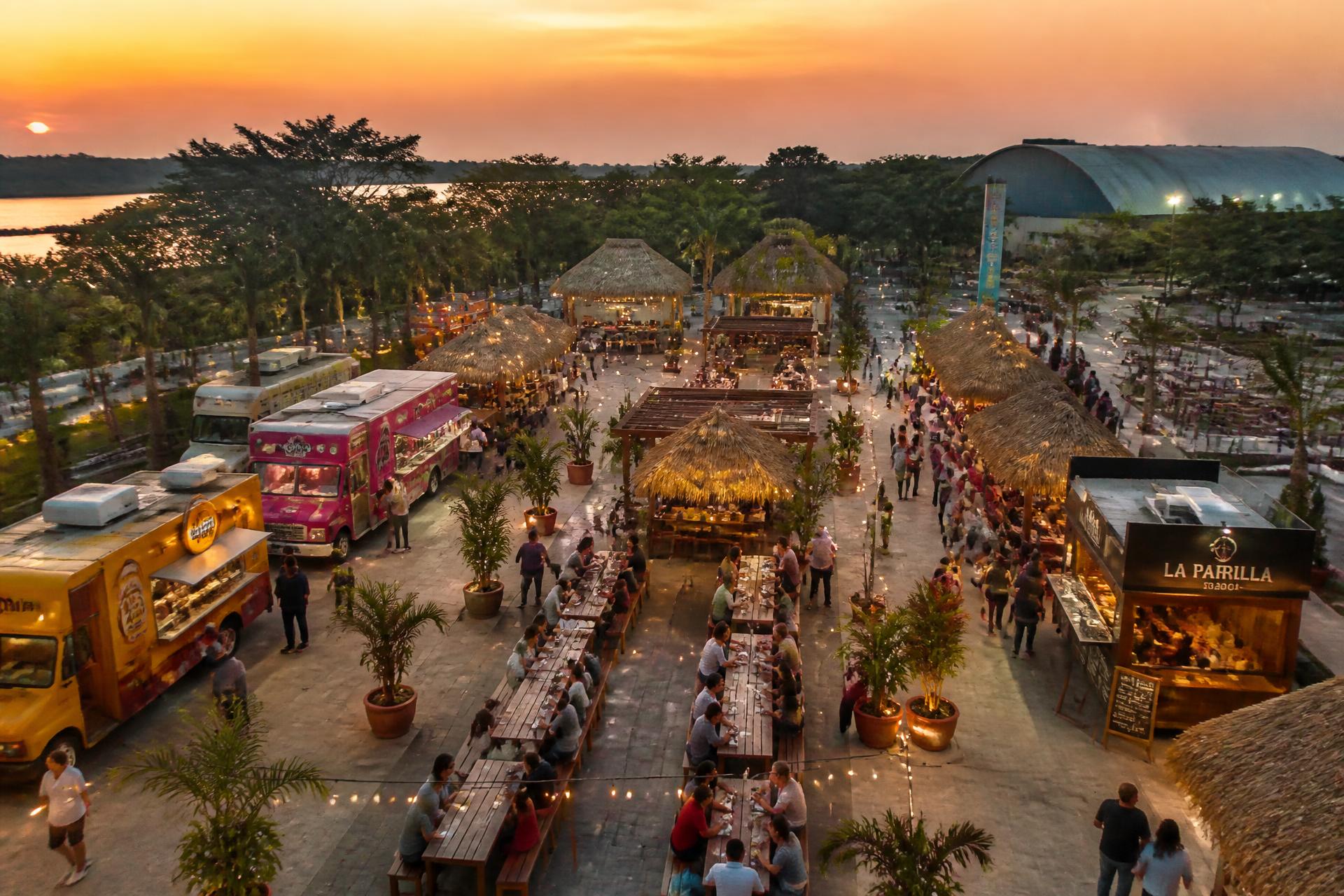 Vista aérea del Food Park al atardecer en Tabasco, con food trucks, palapas y mesas comunales